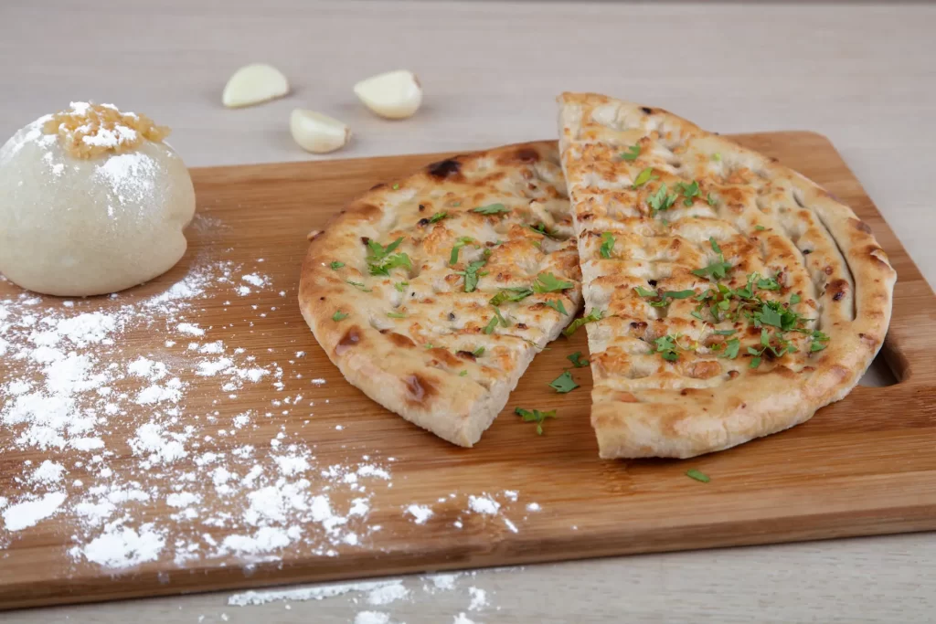 Sliced pizza with cheese and garlic on a wooden cutting board.